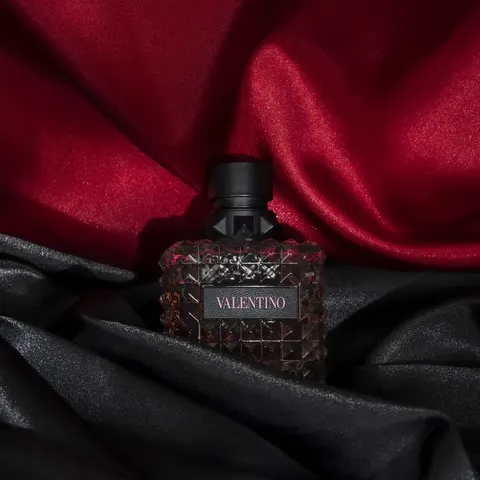 Valentino perfume bottle staged on red and black satin, product shoot for a beauty store