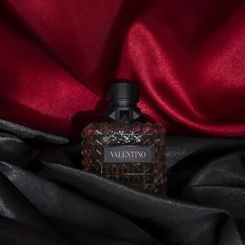 Valentino perfume bottle staged on red and black satin, product shoot for a beauty store